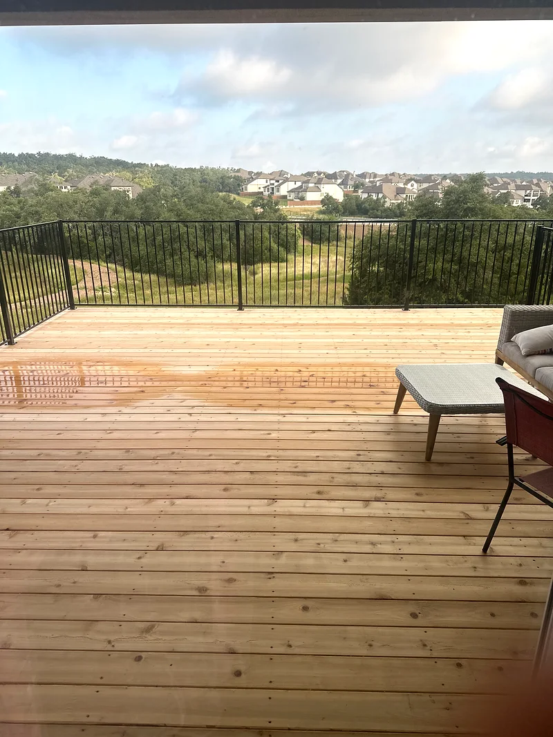Bee Cave deck with stained wood boards, black railing, and Hill Country view