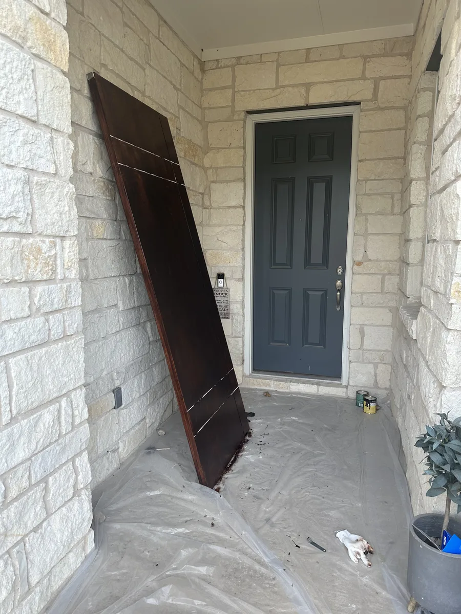 Bee Cave front door work in progress with door surface protected near stone entry and porch floor covering