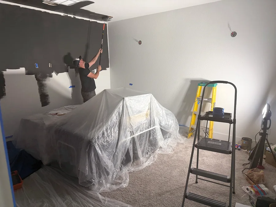 Painter cutting in dark paint near the ceiling of a Dripping Springs media room