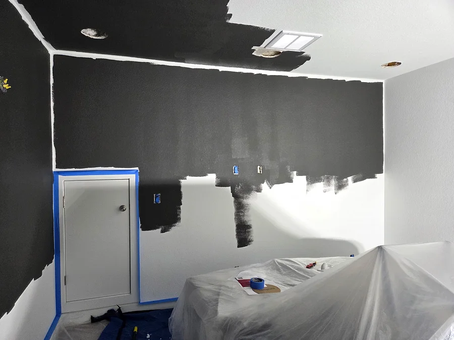 Dark paint being applied to media room walls and ceiling with furniture protected