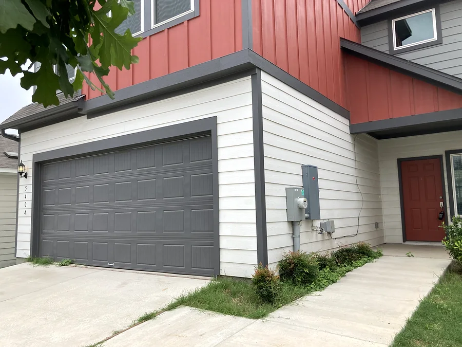 Pflugerville exterior painting detail showing garage door, entry door, siding, trim, and upper accent siding